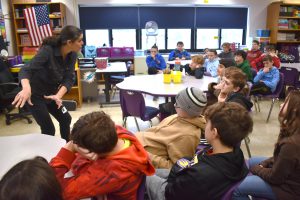 a woman enthusiastically uses hand gestures as she teaches a classroom full of students