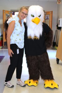 a woman stands next to a mascot dressed up as an eagle