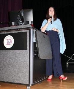 a woman wearing a blue shawl talks into a microphone on a stage