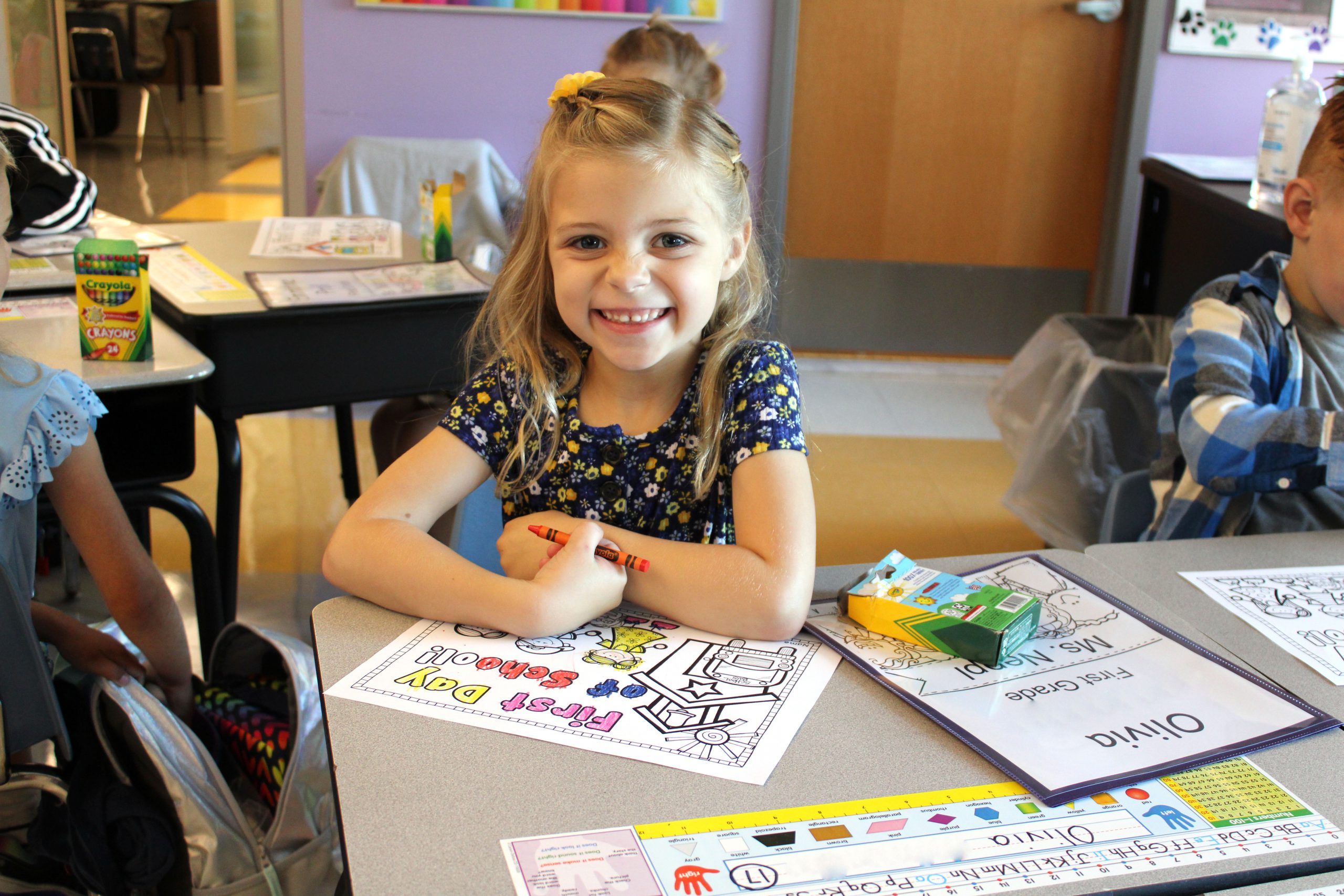 a young girl colors a picture while sitting at a desk