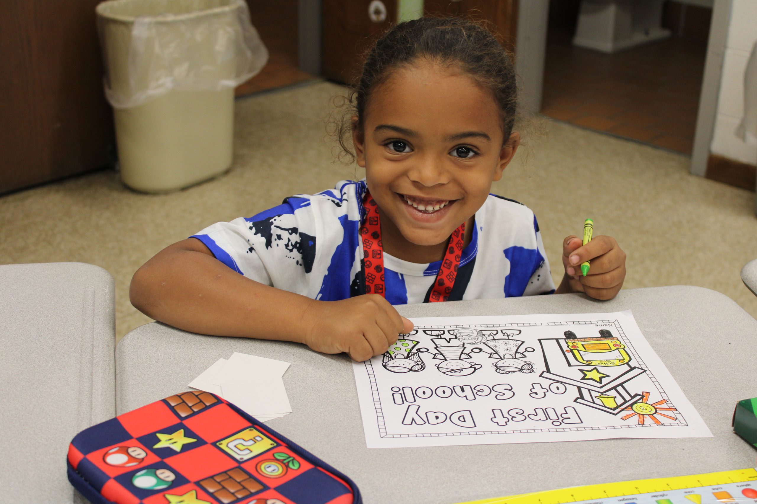 a young boy smiles while coloring in a picture