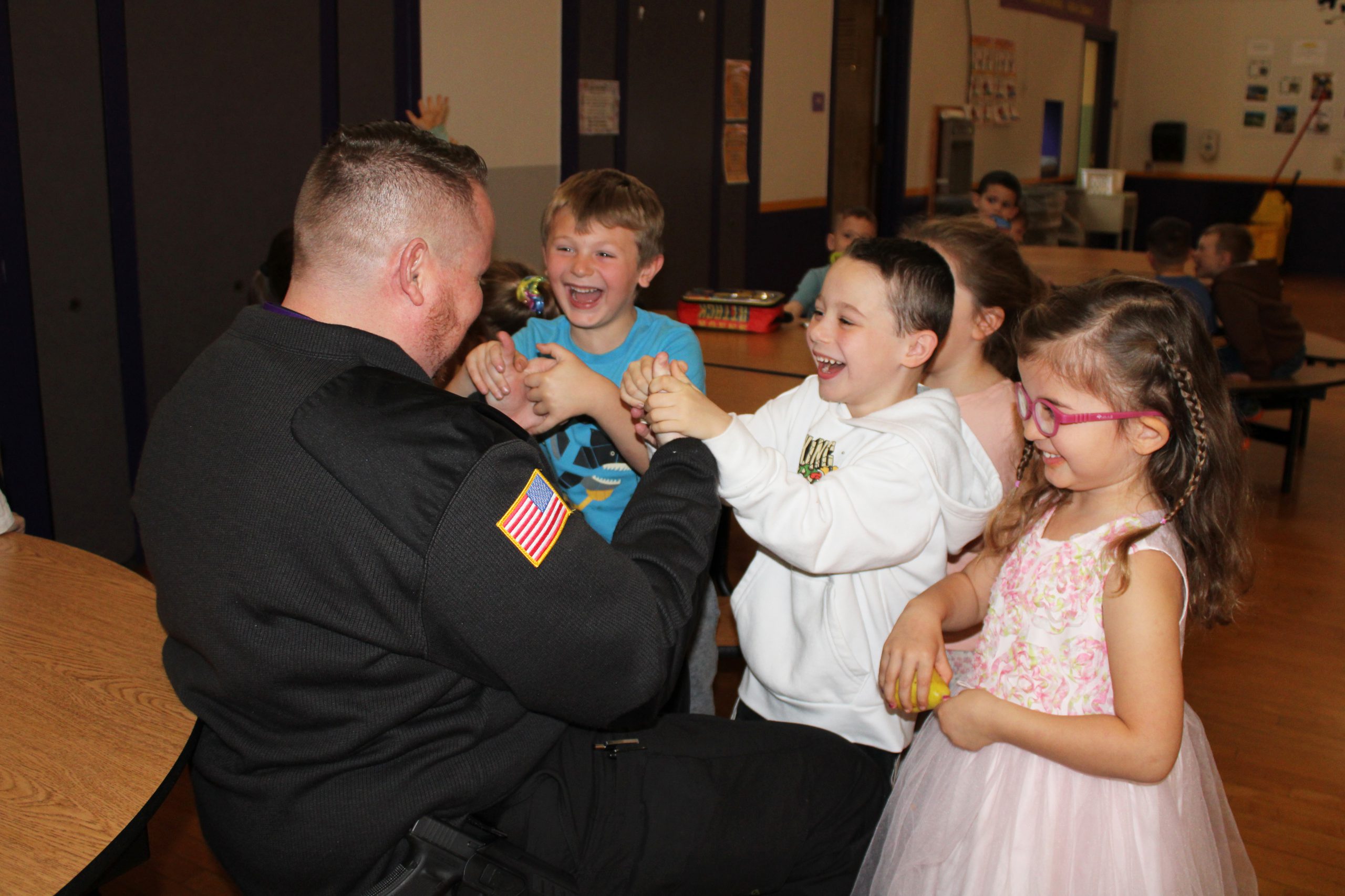 a man plays thumb war with several elementary students in the cafeteria