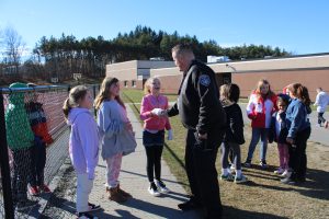 a police officer shakes the hand of a young elementary age child