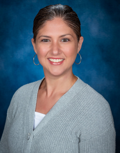 a woman wearing a gray cardigan smiles