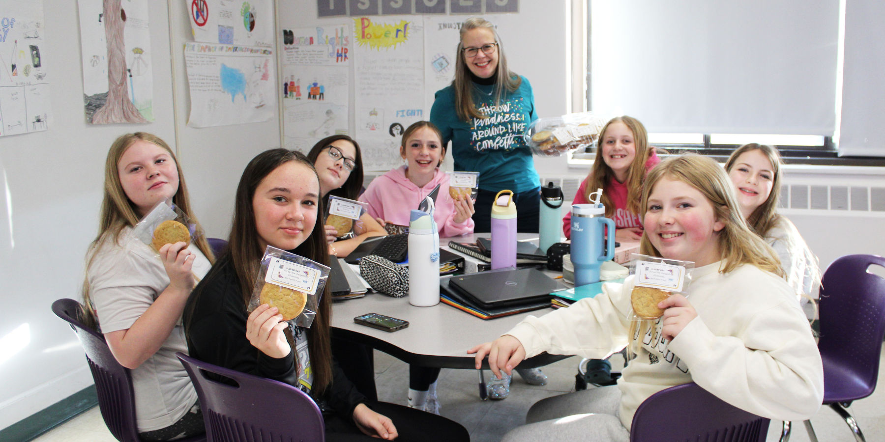 a woman hands out cookies to a group of teenaged girls