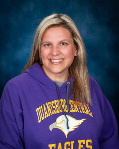 a woman with blonde hair wears a purple sweatshirt